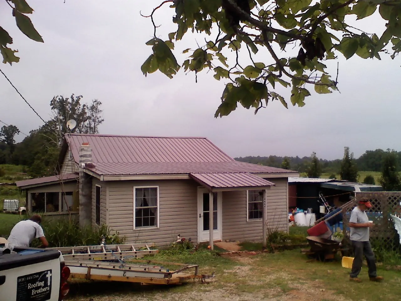 Crew finishing a mauve metal roof on a small farmhouse in Alum Bank