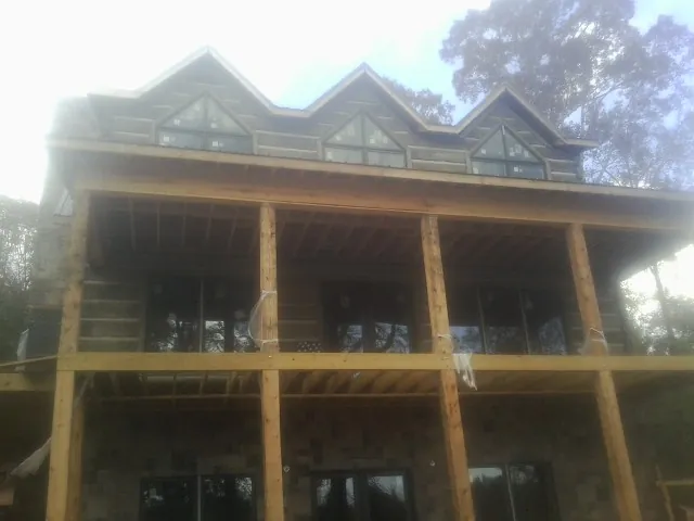 Dormers and porch framing on a large log home under construction — Roof Coating work by our crew in Alum Bank
