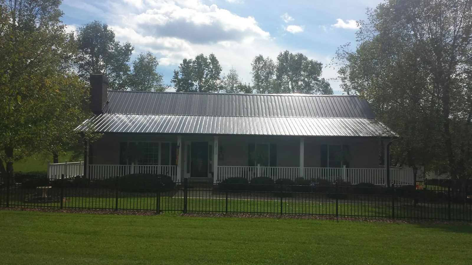 Gray metal roof on a brick ranch with a full width front porch — Gutter Guard Installation work by our crew in Alum Bank