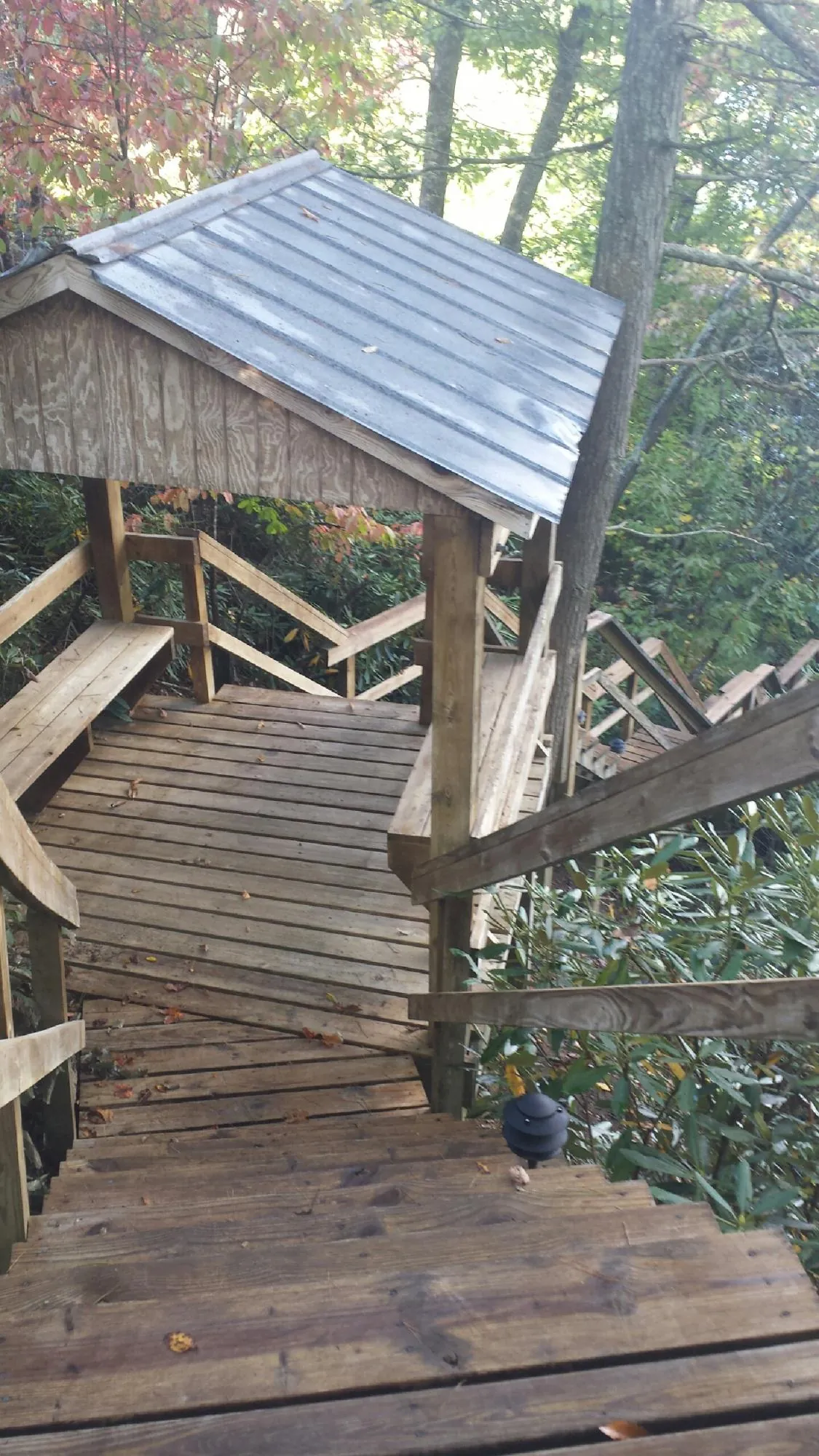 Metal roofed shelter over wooden steps on a wooded walkway — Skylight Repair & Installation work by our crew in Alum Bank