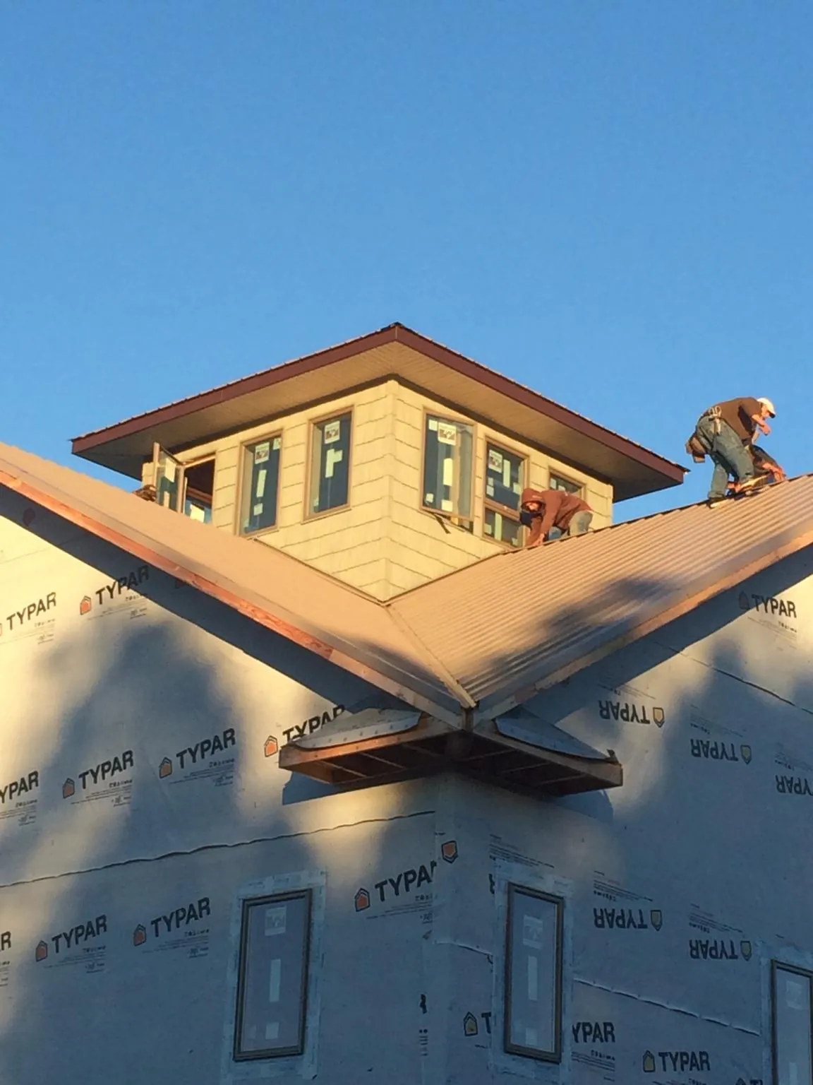Roofers working around a rooftop cupola on a new metal roof at sunset — Roof Waterproofing in Alum Bank by Roofing Brothers